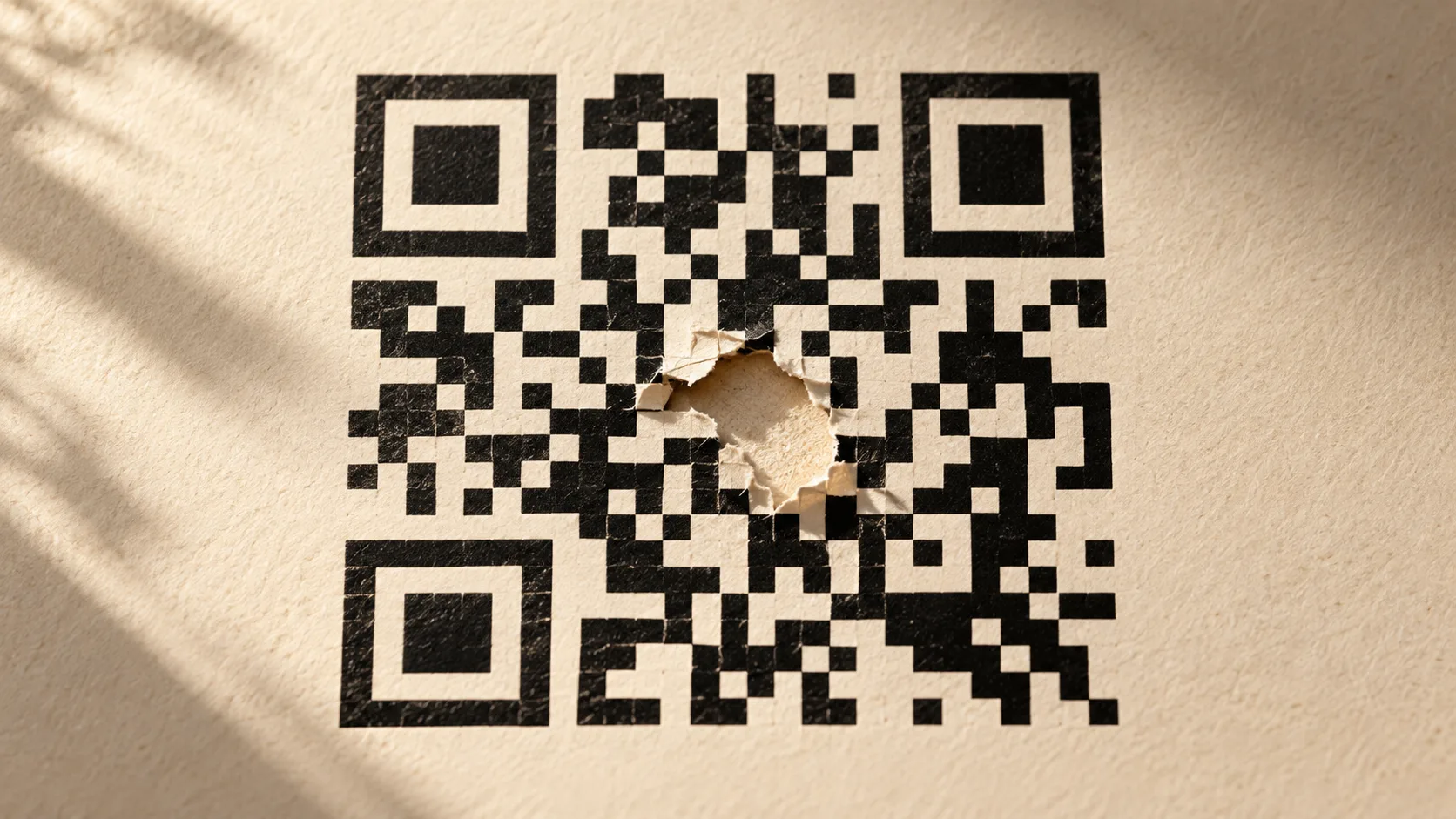 紙上黑白 QR 碼示意圖中央有一小塊破損，三個角落的定位方框保持完整